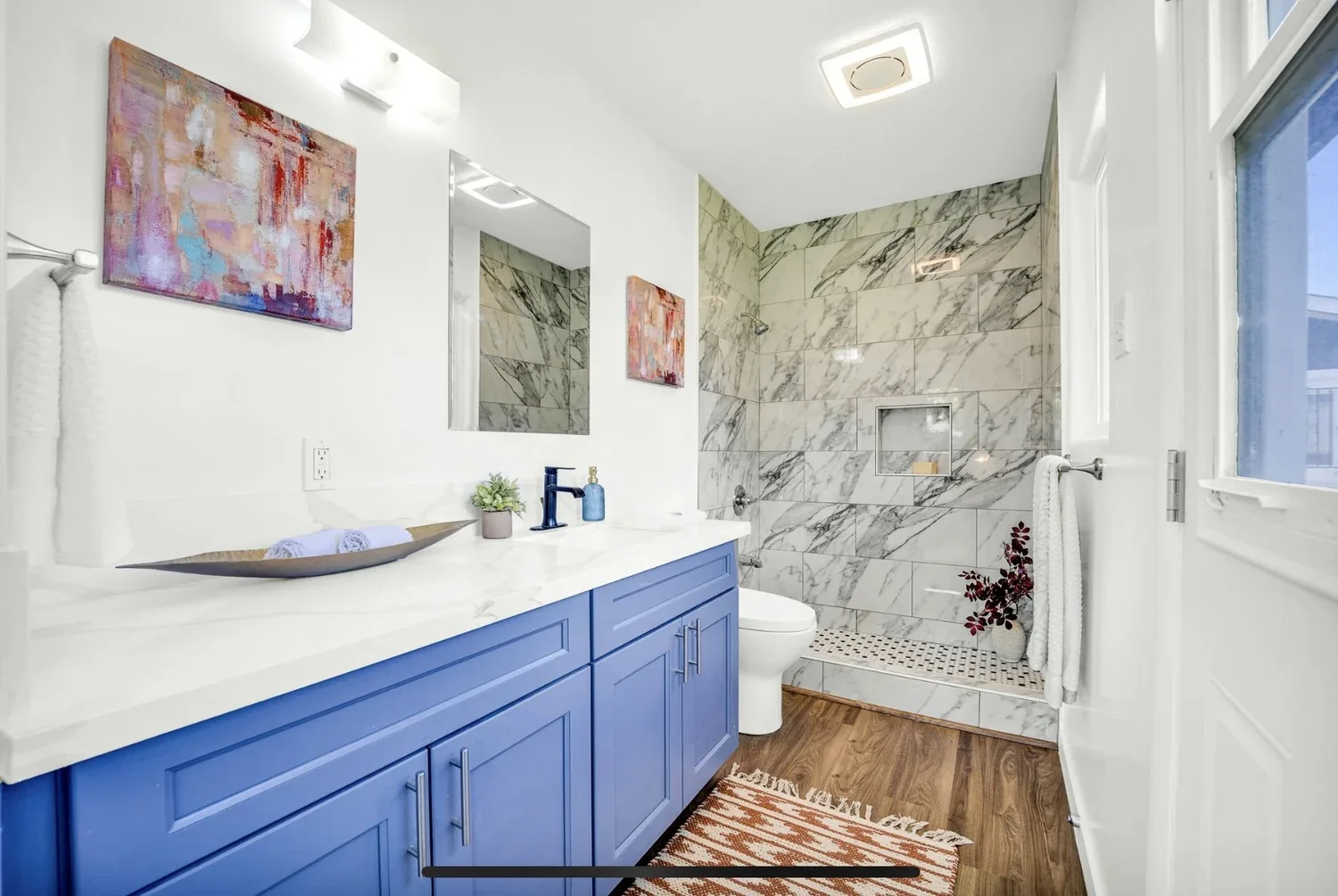 Bathroom with blue double vanity and marble tile